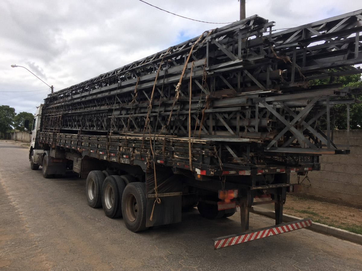 Caminhão carregado com treliças metálicas montadas, empilhadas e amarradas para seguir até a galvanização